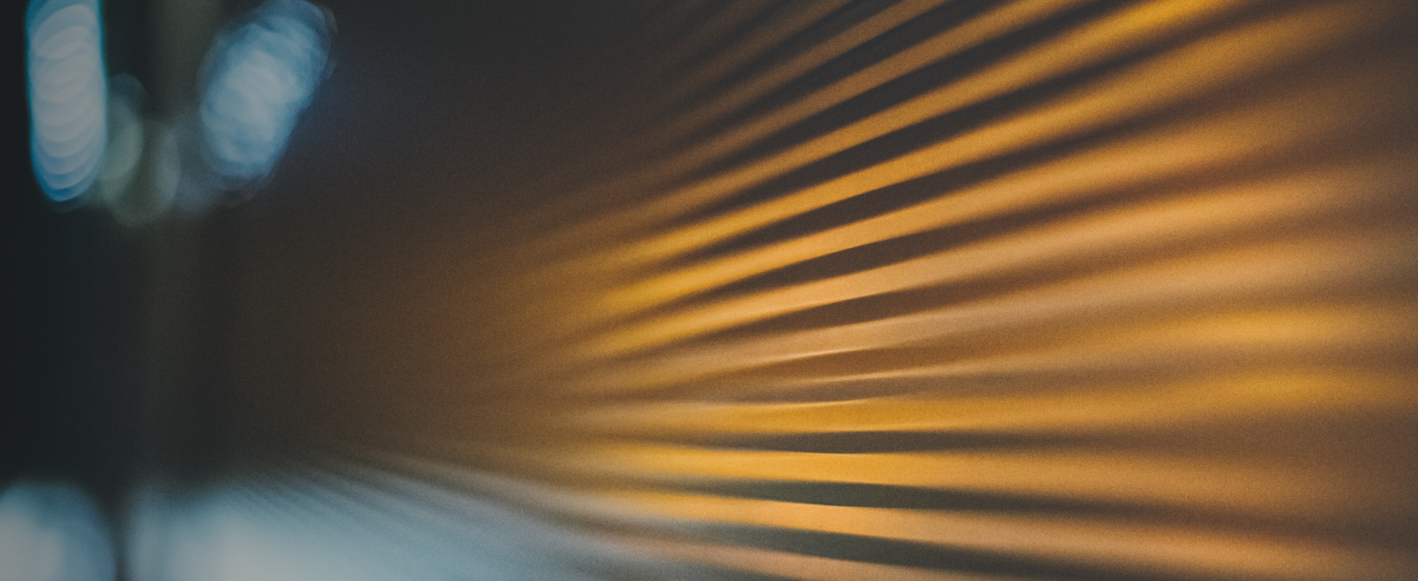 Close-up of diagonal lines with shadows in warm golden tones on a textured surface.