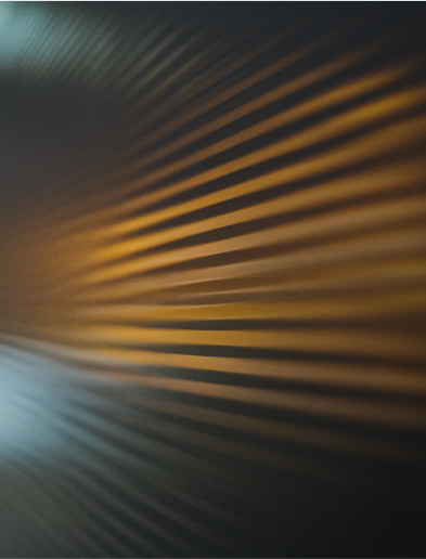 Close-up of diagonal lines with shadows in warm golden tones on a textured surface.