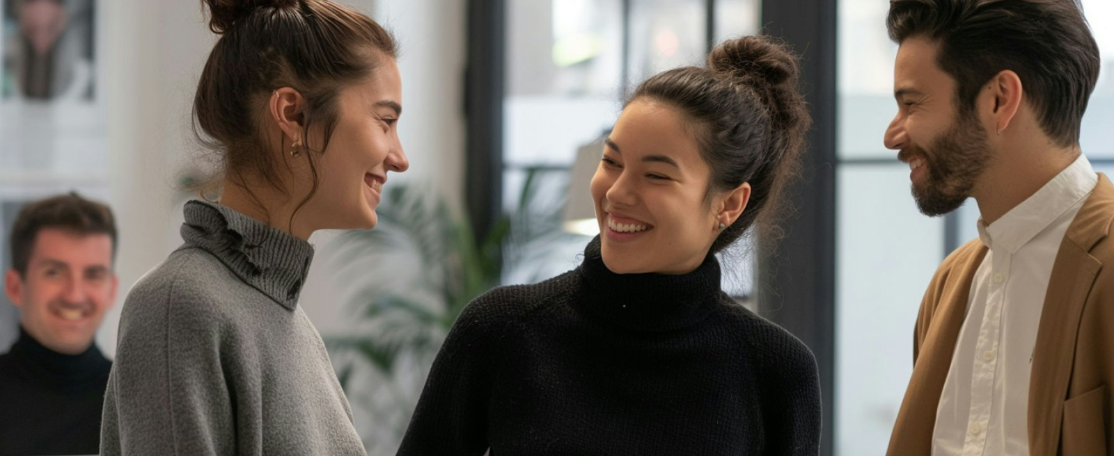 Three people smiling and talking indoors.