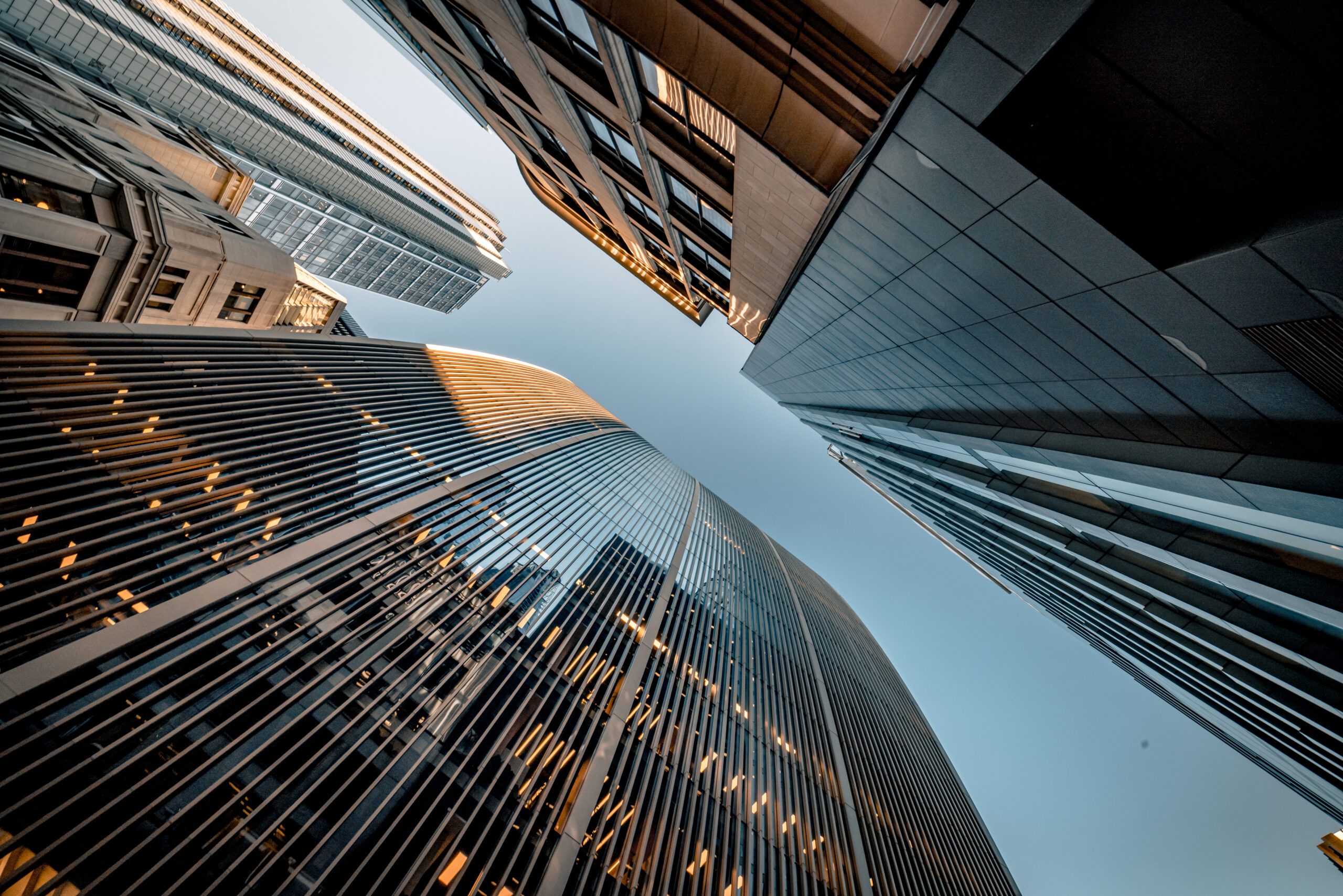 Upward view of several modern skyscrapers with clear blue sky in between.
