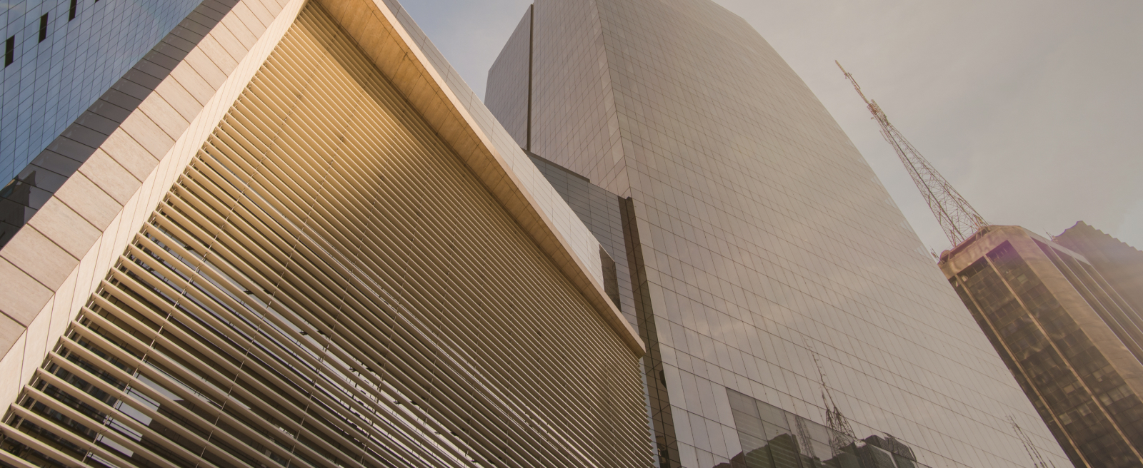 Low-angle view of modern skyscrapers in Latin America with louvered and glass facades under a clear sky.