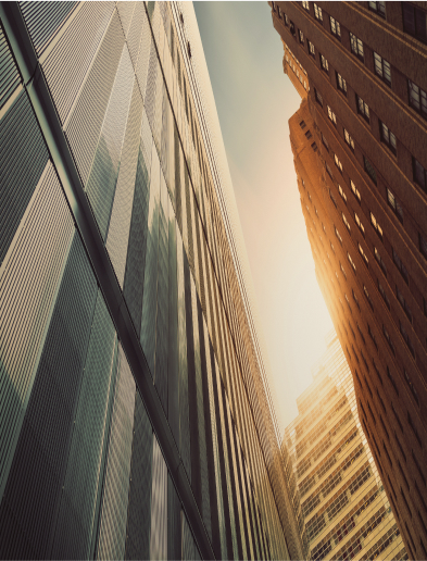 View from below of three tall buildings in North America with sun shining between them.