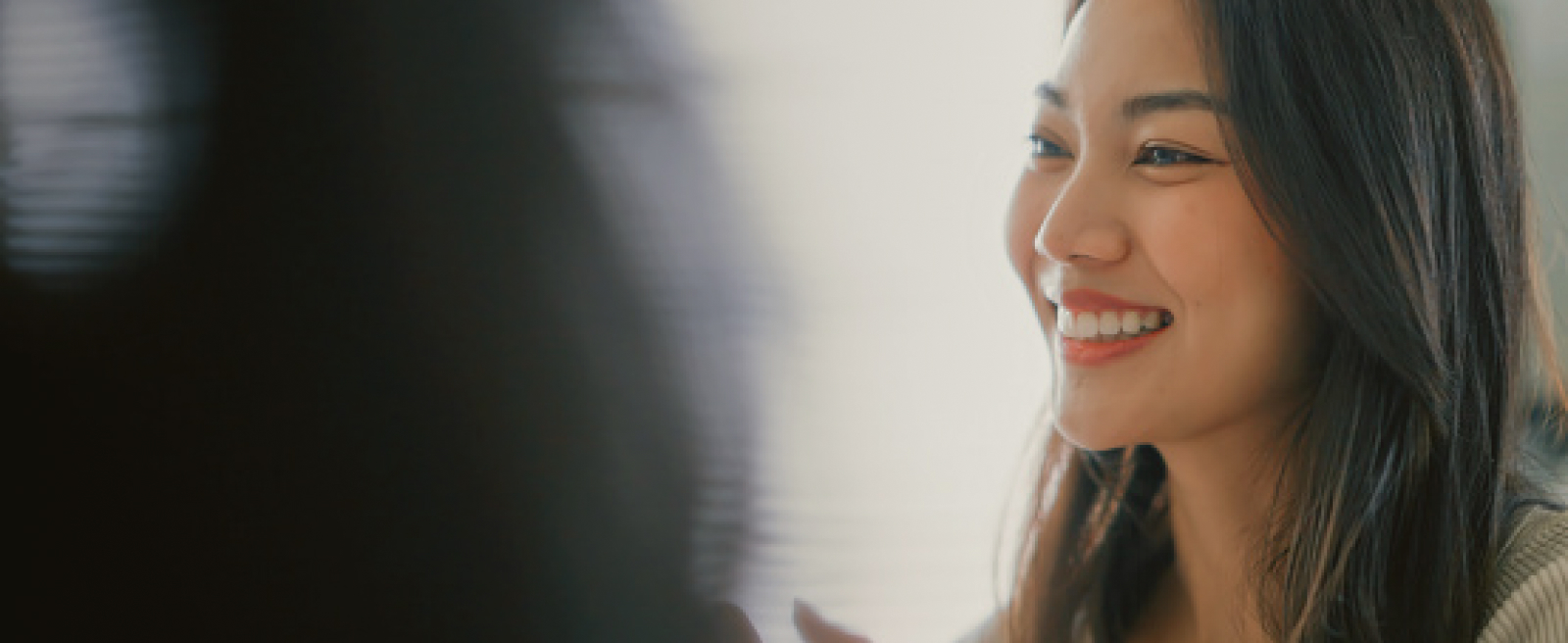 Profile view of a smiling woman with long dark hair.