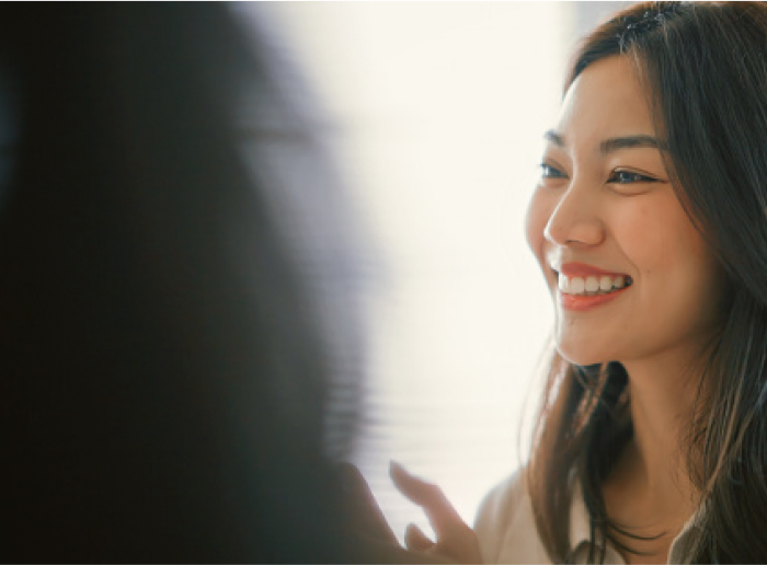 Profile view of a smiling woman with long dark hair.
